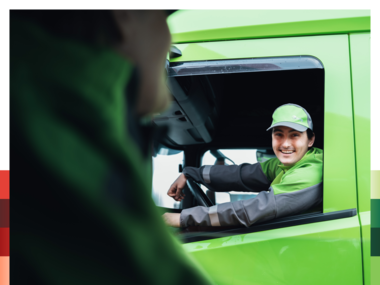 Bring sjåfør sitter i lastebil og smiler til kollega